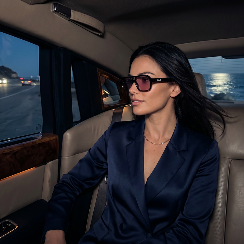 wealthy young woman sitting an a fancy car wearing rose harbour eyewear